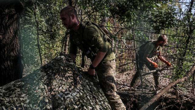 Ukrainian servicemen camouflage a self propelled howitzer after firing towards Russian troops in Donetsk region