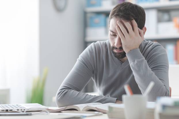 Exhausted,Young,Man,Working,At,Office,Desk,And,Touching,His