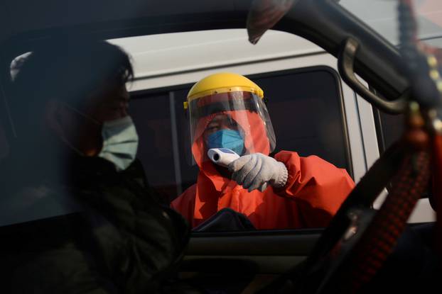 FILE PHOTO: Worker in protective suit checks temperature of a truck driver entering the Xinfadi wholesale market, as the country is hit by an outbreak of the novel coronavirus disease (COVID-19), in Beijing