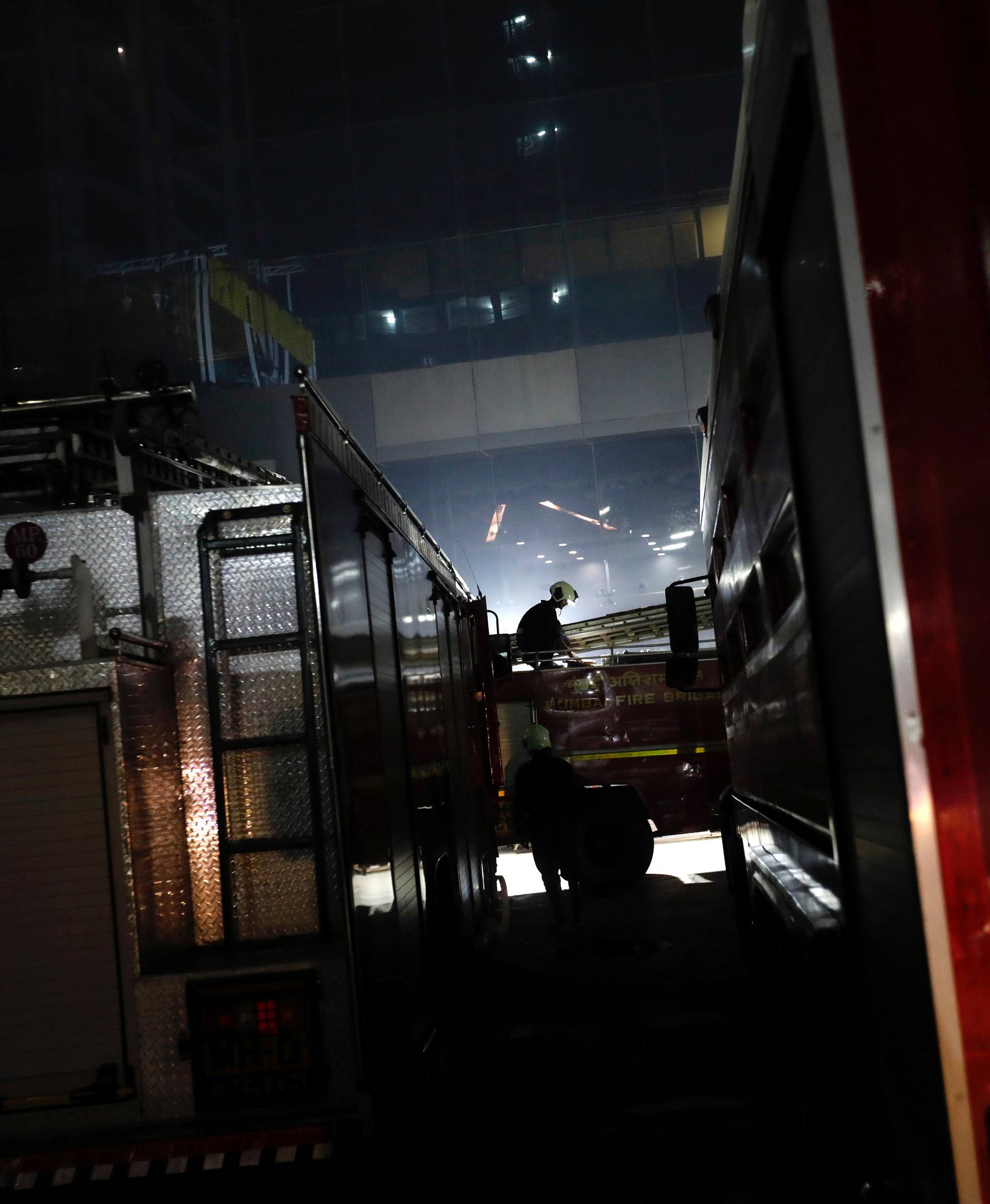 A fireman sits on a fire engine as others try to douse a fire at a restaurant in Mumbai