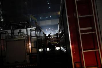 A fireman sits on a fire engine as others try to douse a fire at a restaurant in Mumbai