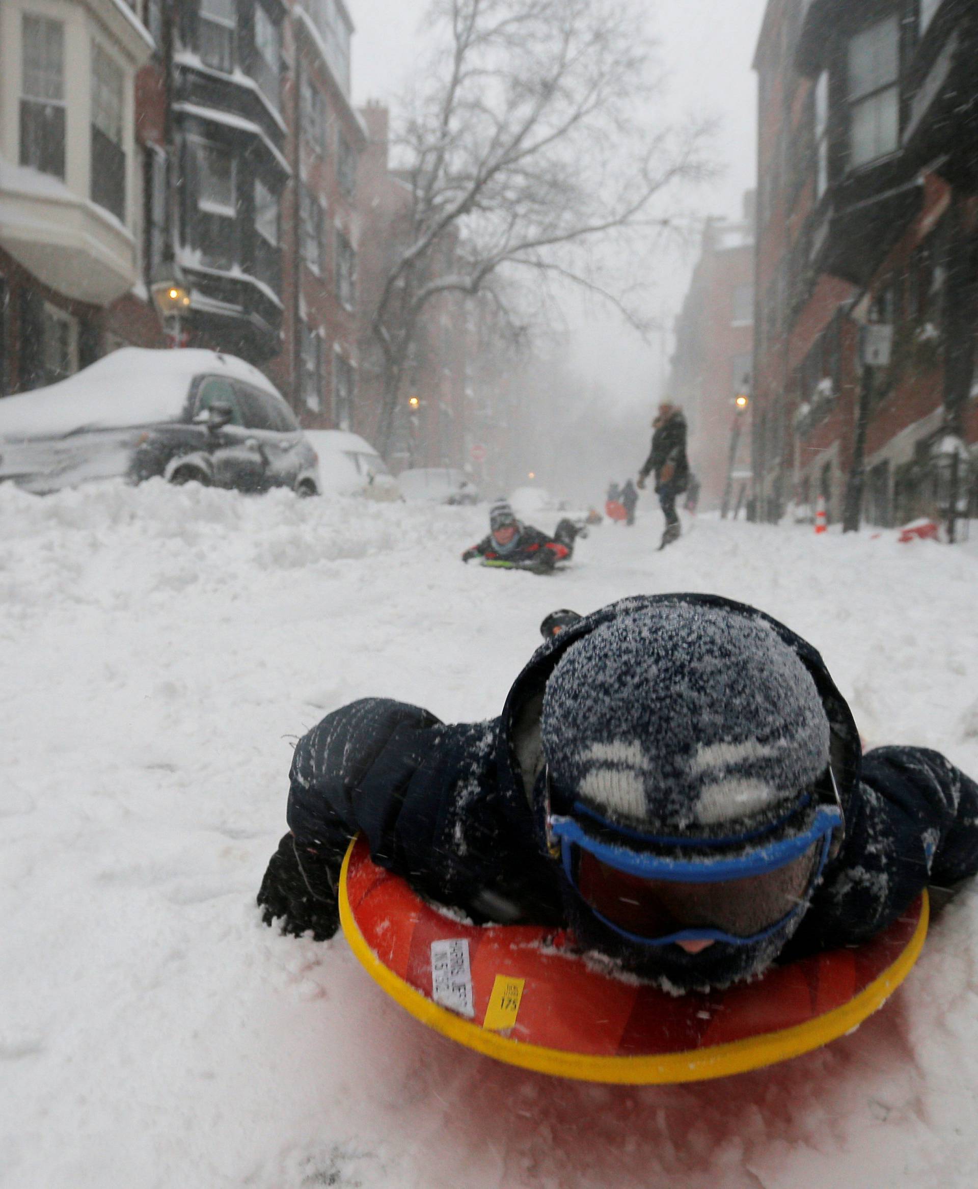 A boy sleds down a Beacon Hill street during Storm Grayson in Boston