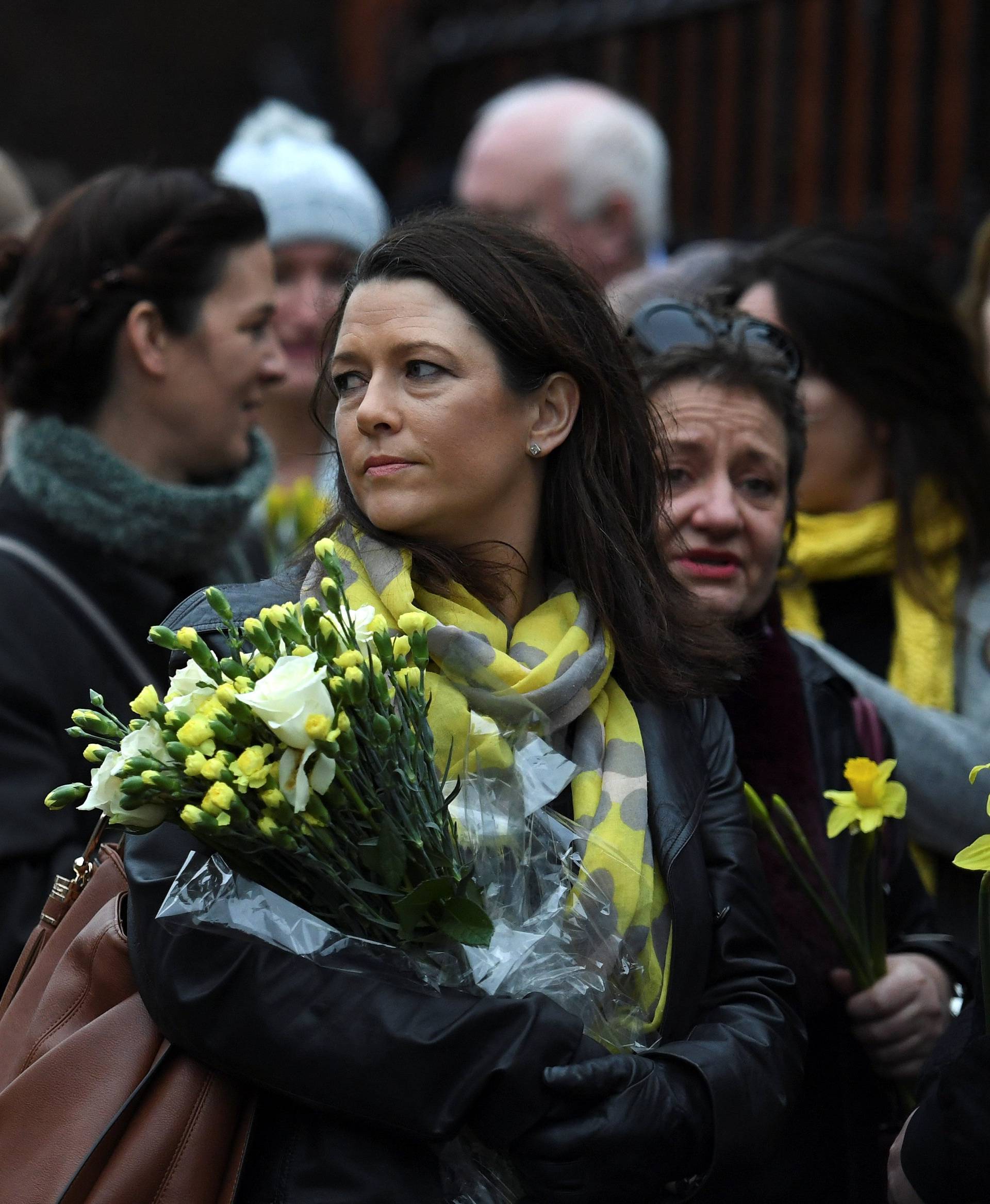 Schoolfriends bring yellow flowers to represent sunshine as they queue up to view Cranberries singer Dolores O'Riordan's coffin as it is carried into St. Joseph's Church for a public reposal in Limerick