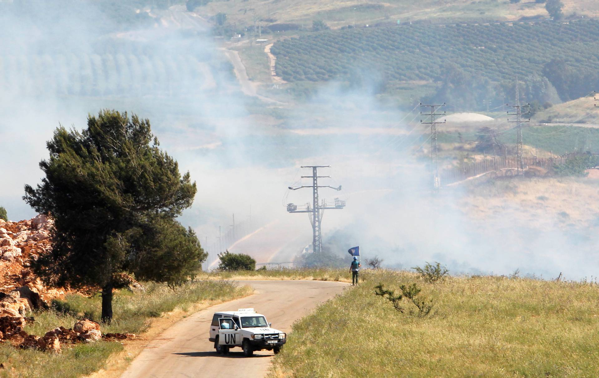 A UN peacekeeper (UNIFIL) stands as smoke rise in the southern Lebanese village of Khiam