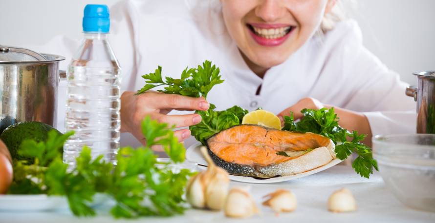 Happy young cook with prepared trout in plate