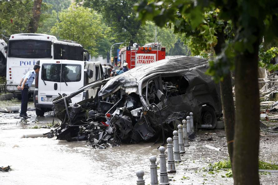 A destroyed van is pictured near a Turkish police bus which was targeted in a bomb attack in a central Istanbul district