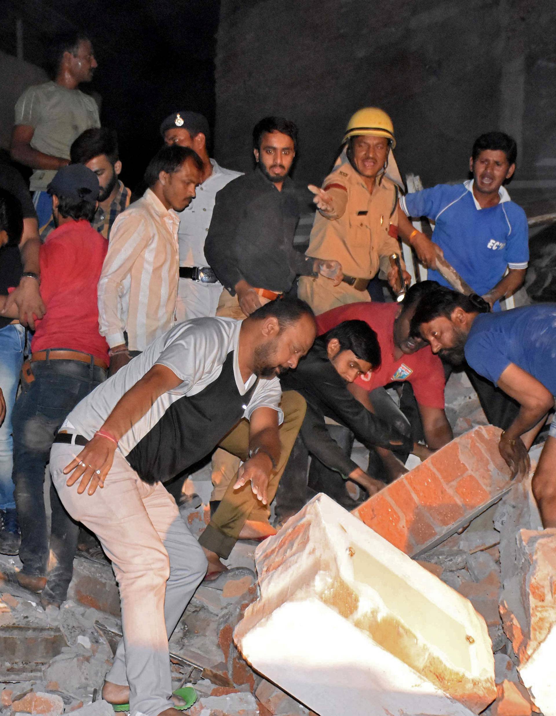 People remove the debris as they search for survivors at the site of a collapsed hotel building in Indore