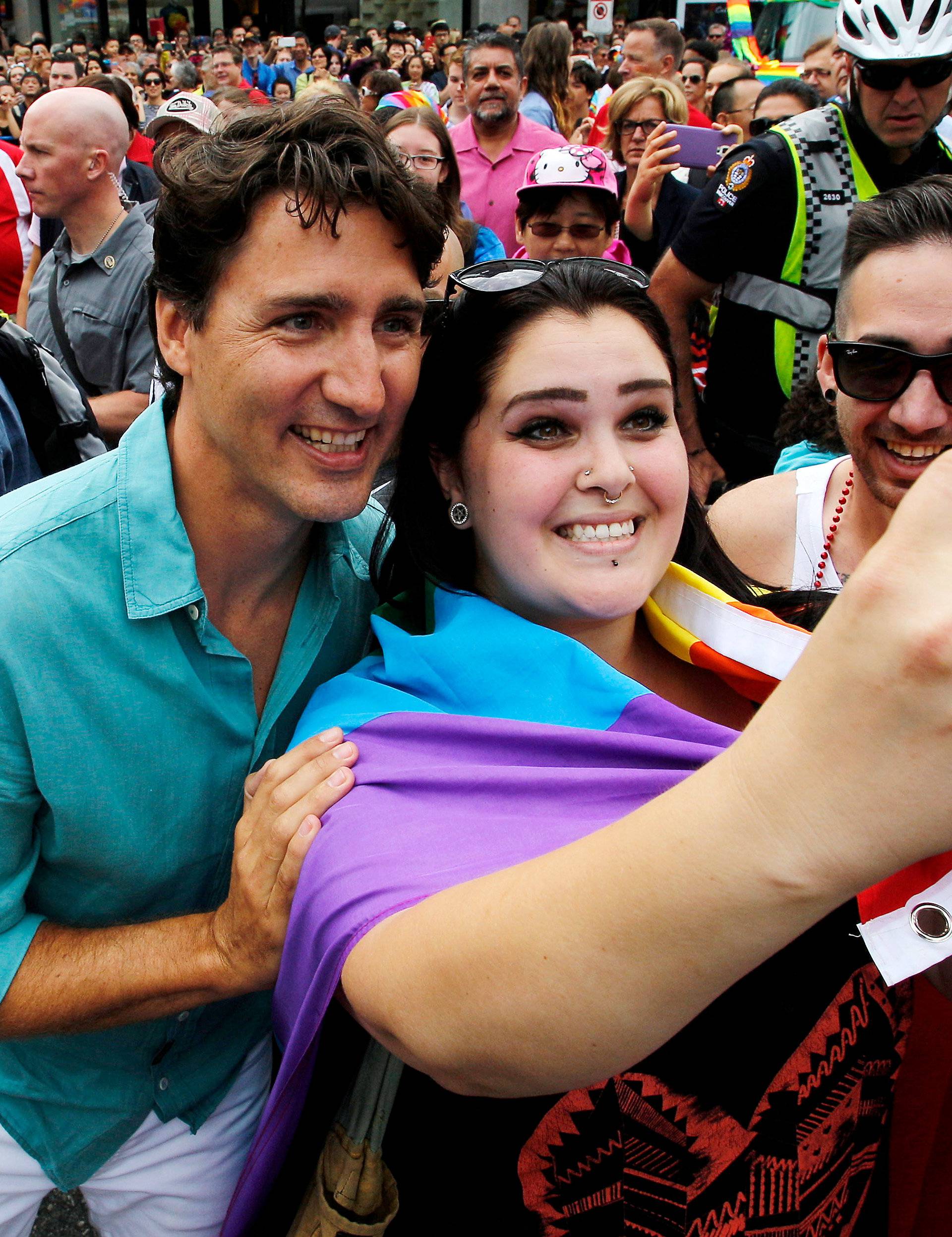 Canada's Prime Minister Justin Trudeau takes a picture with a supporter while walking in the Vancouver Pride Parade with his family