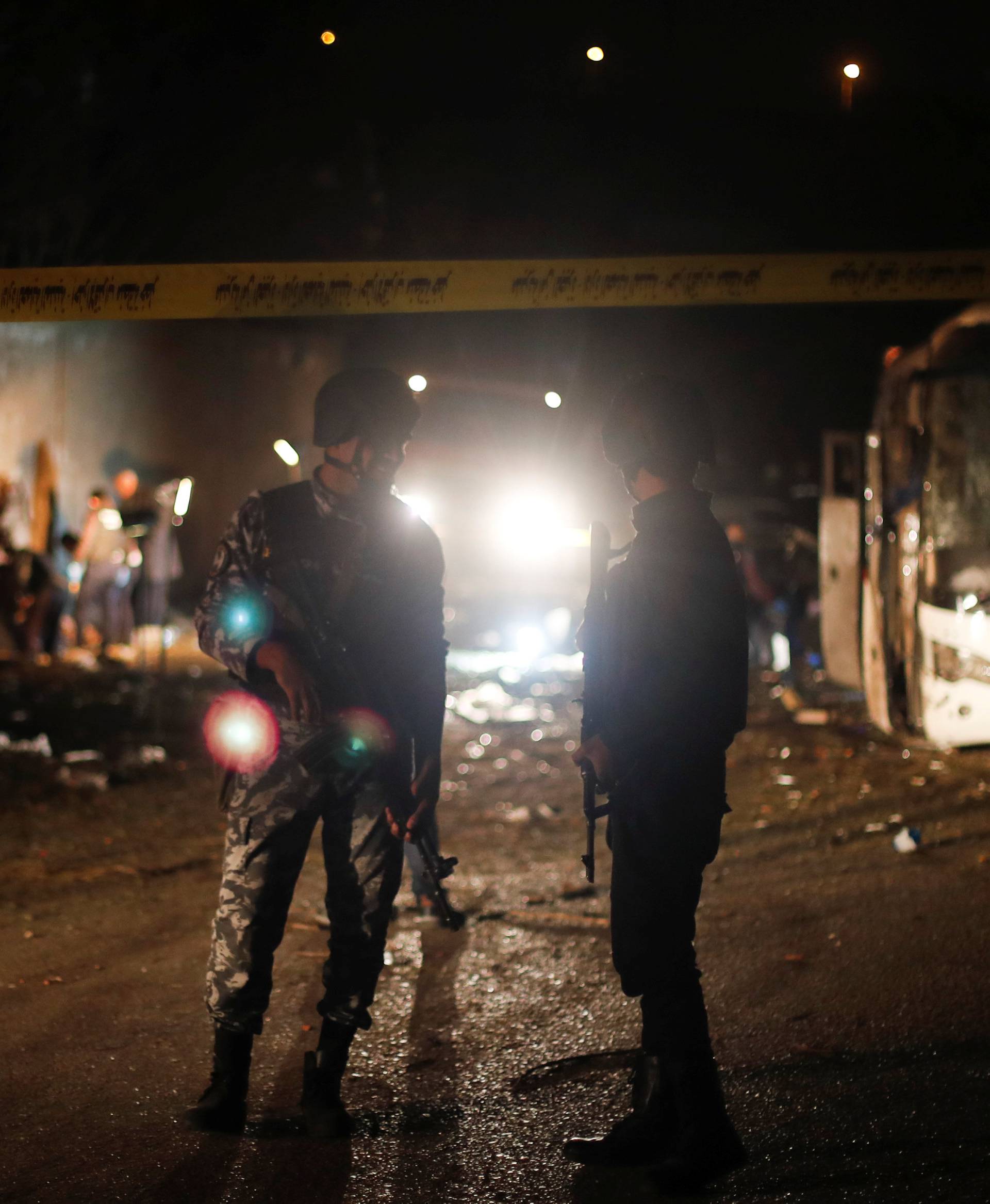 Police officers inspect a scene of a bus blast in Giza