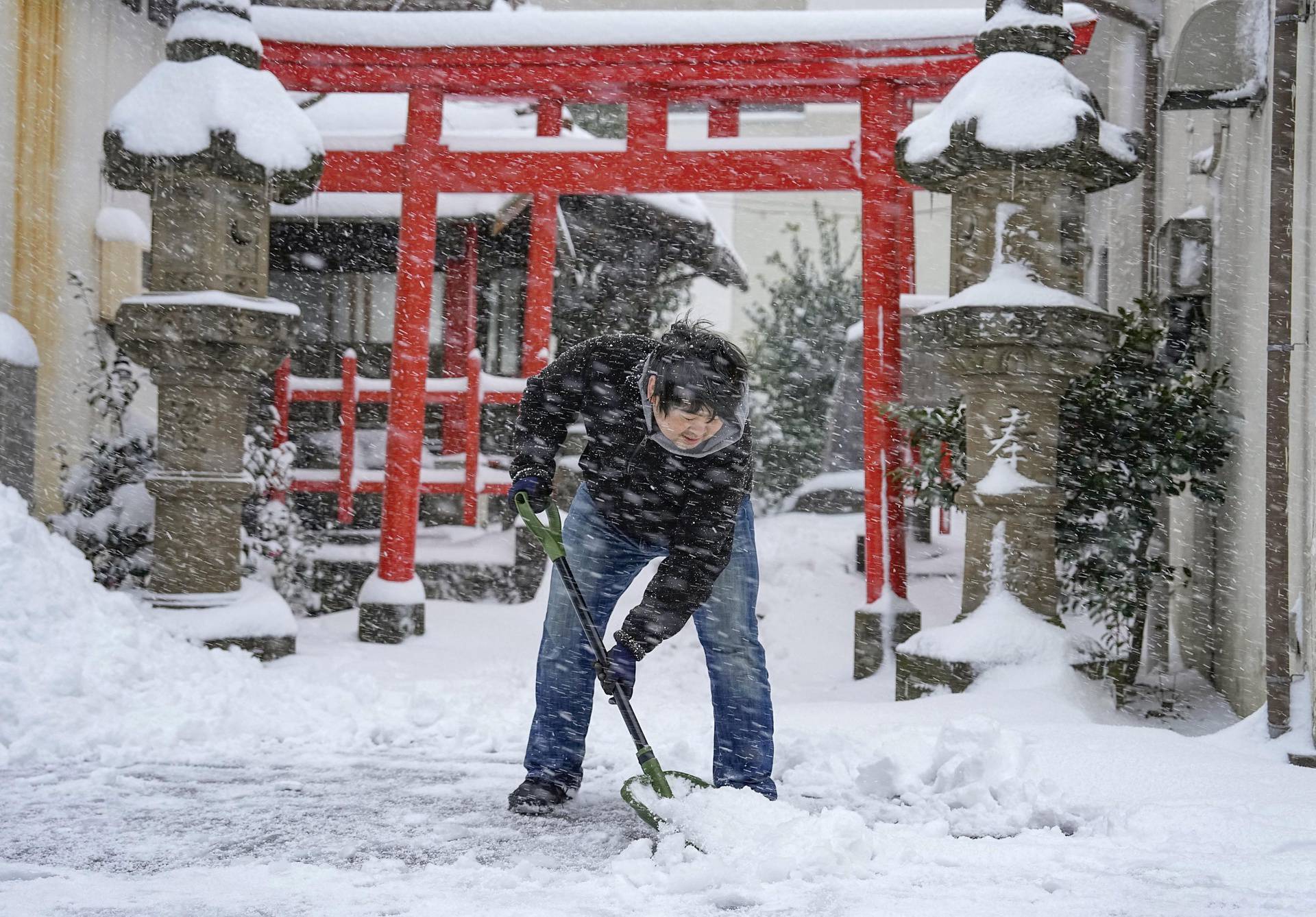 A man clears snow in front of a shrine amid heavy snowfall in Tottori