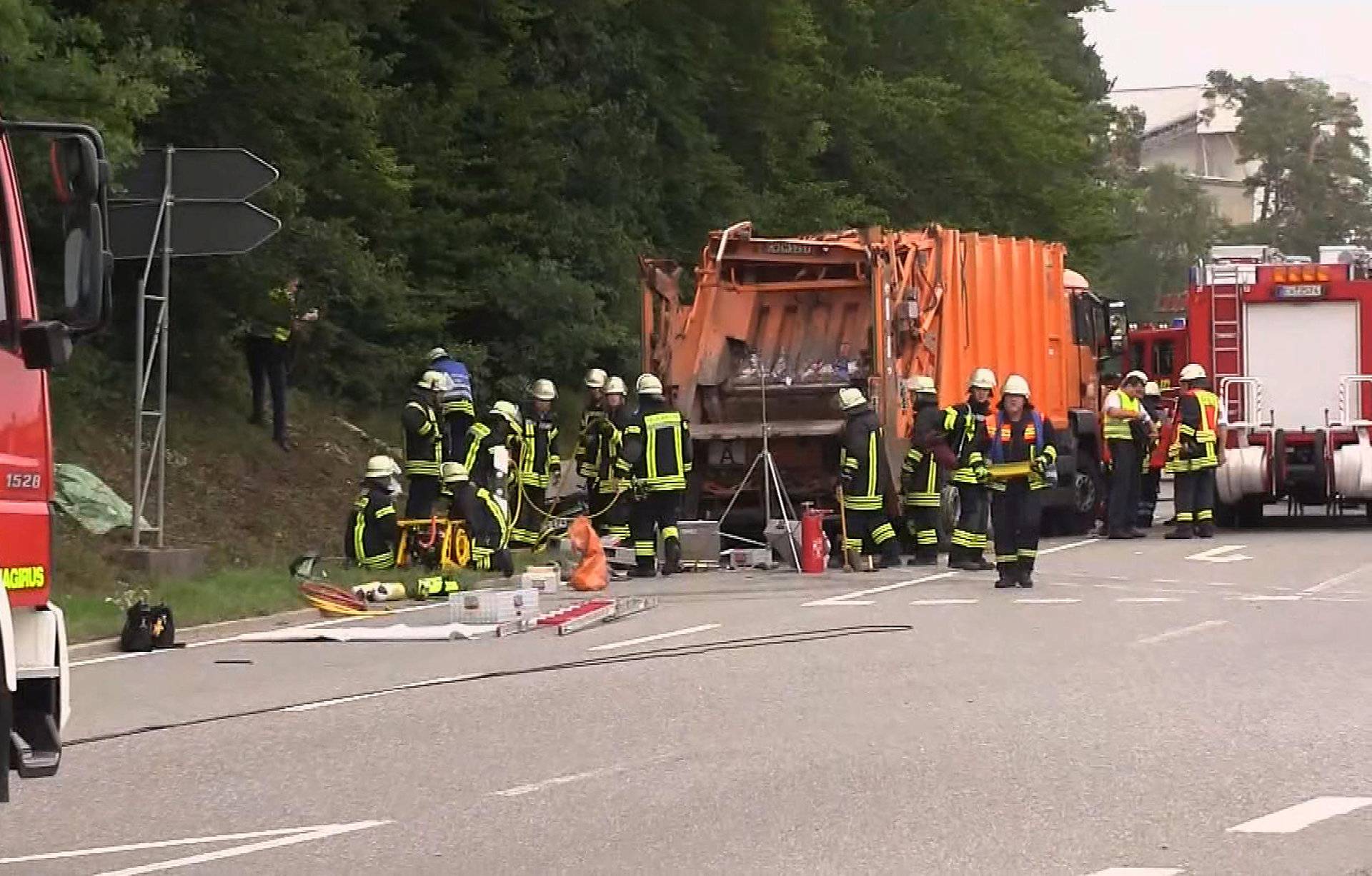 A still image taken from a video shows firefighters at a garbage truck which tipped over and landed on a car in Nagold