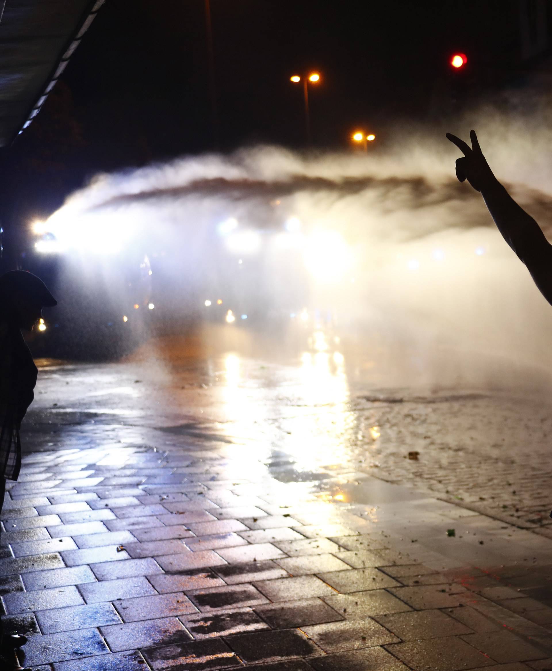 A protester shows V-sign as German police use water cannon during the demonstration at the G20 summit in Hamburg
