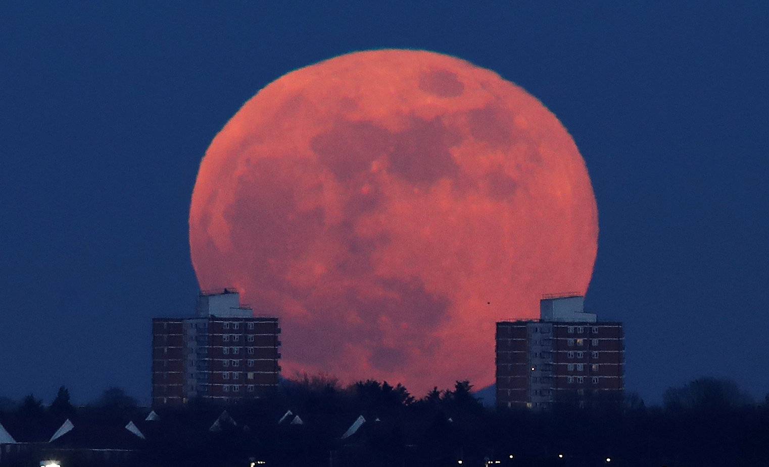 A full moon rises behind blocks of flats in north London,