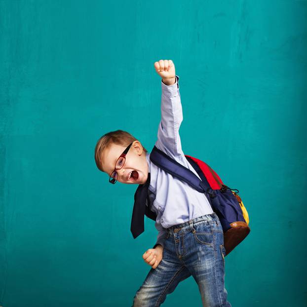 smiling little boy with big backpack jumping and having fun