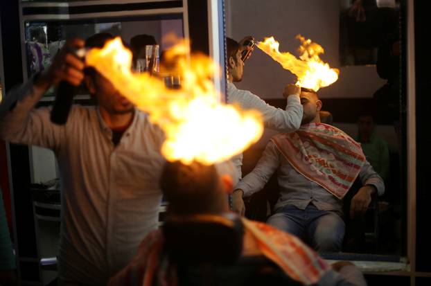 Palestinian barber Ramadan Odwan styles and straightens the hair of a customer with fire at his salon in Rafah, in the southern Gaza Strip