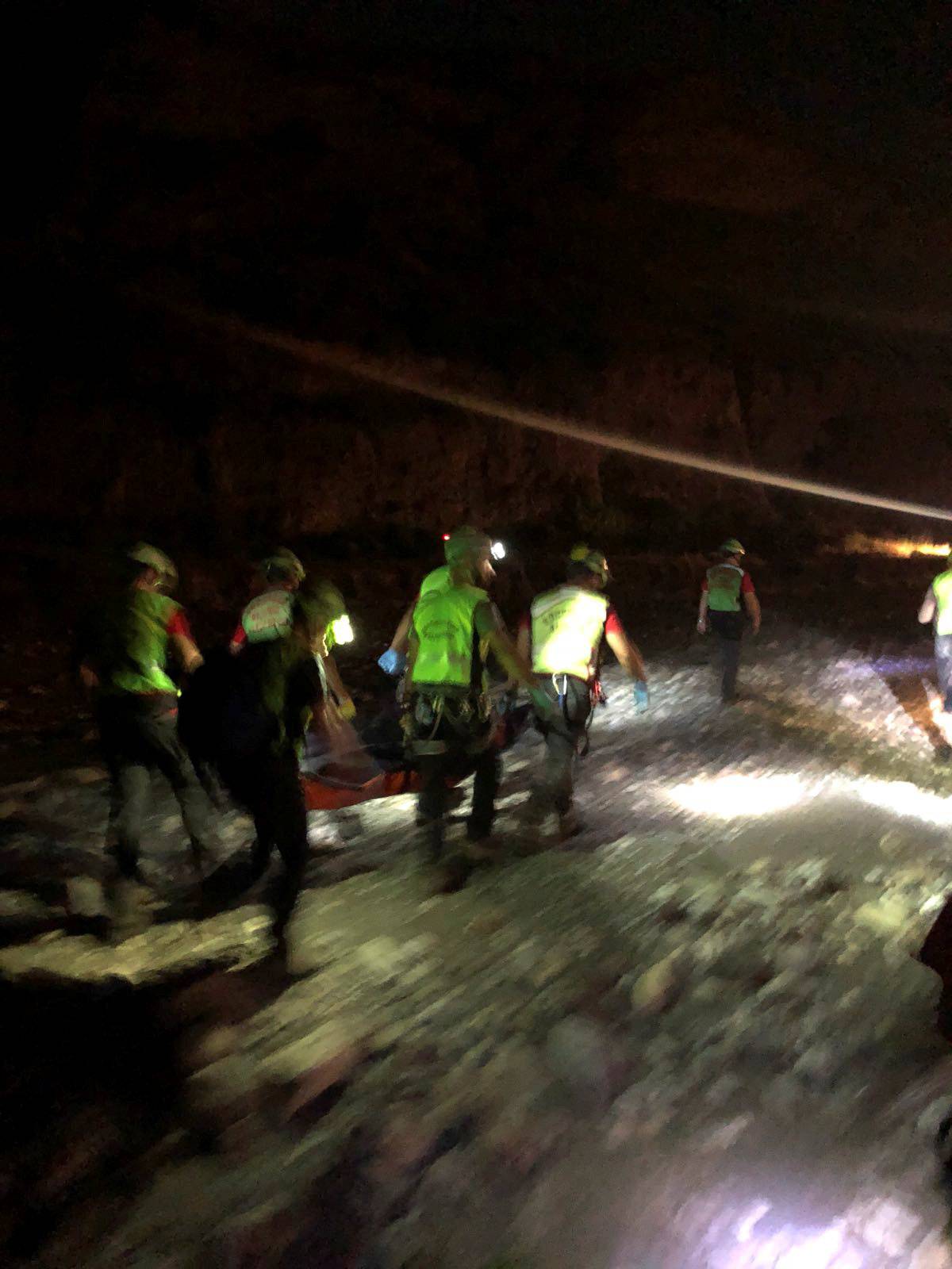Alpine rescue workers carry a body after several people were killed in a mountain gorge flooding, in the municipality of Civita