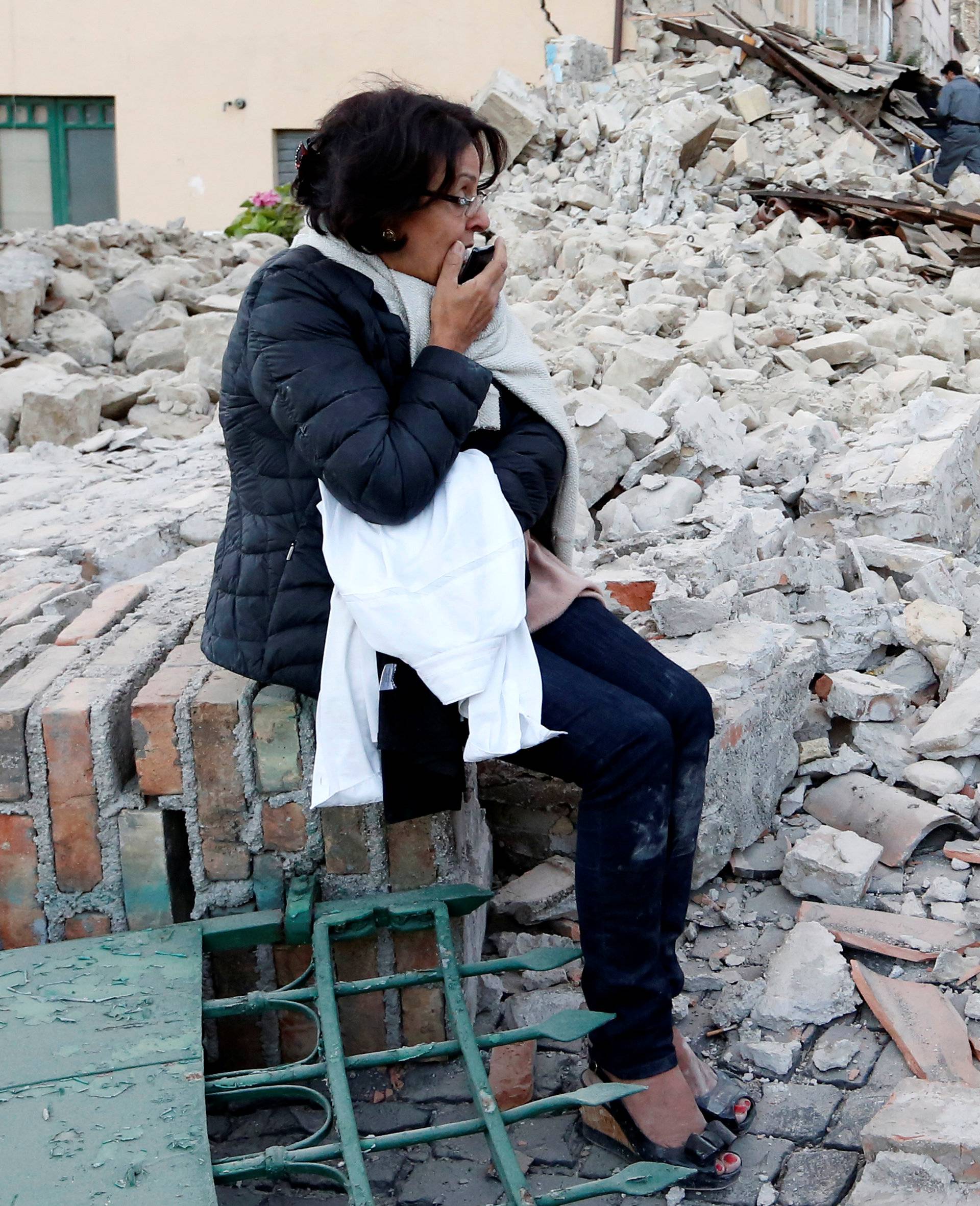 A woman sits amongst rubble following a quake in Amatrice