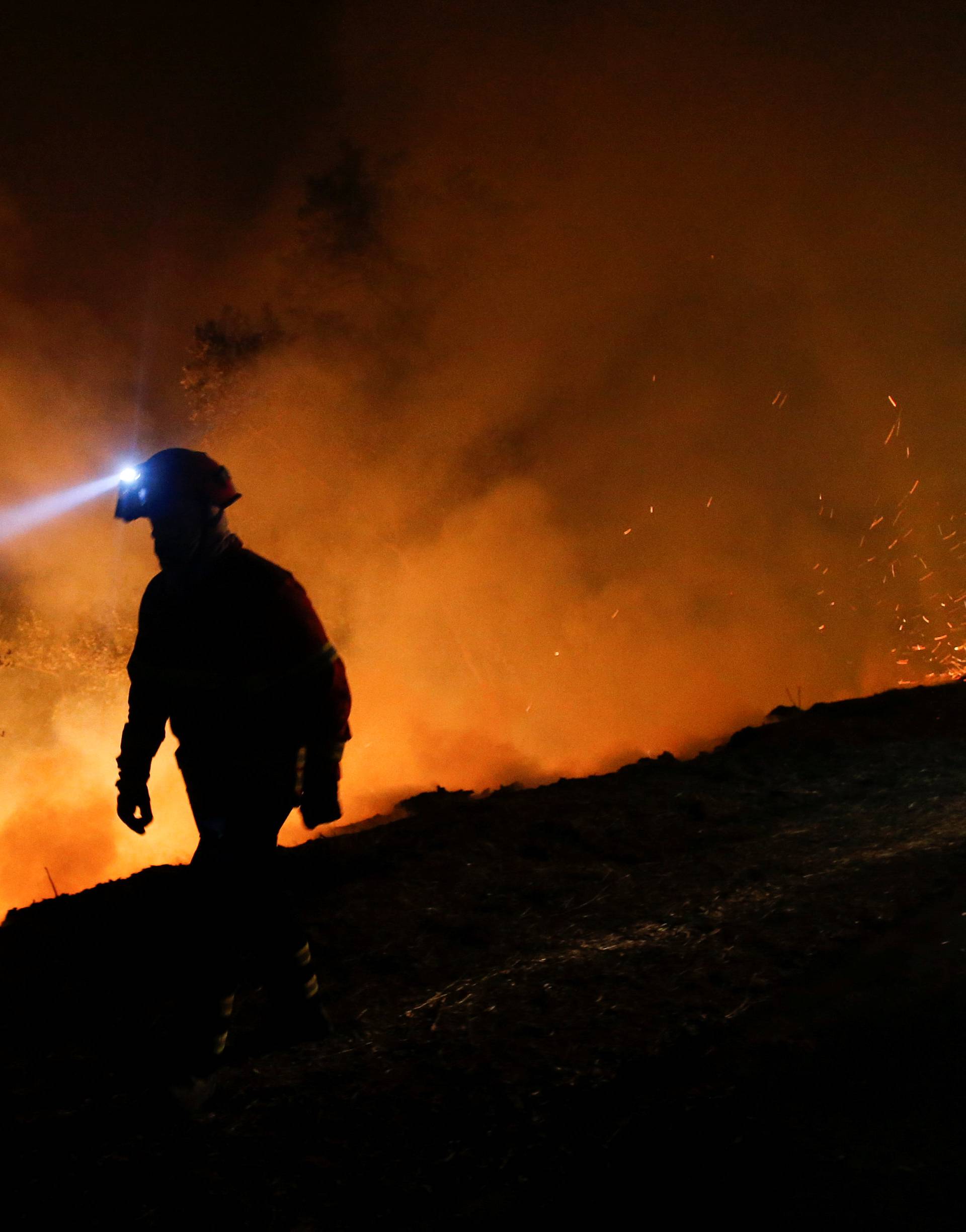 A firefighters works to extinguish flames from a forest fire in Cabanoes near Lousa