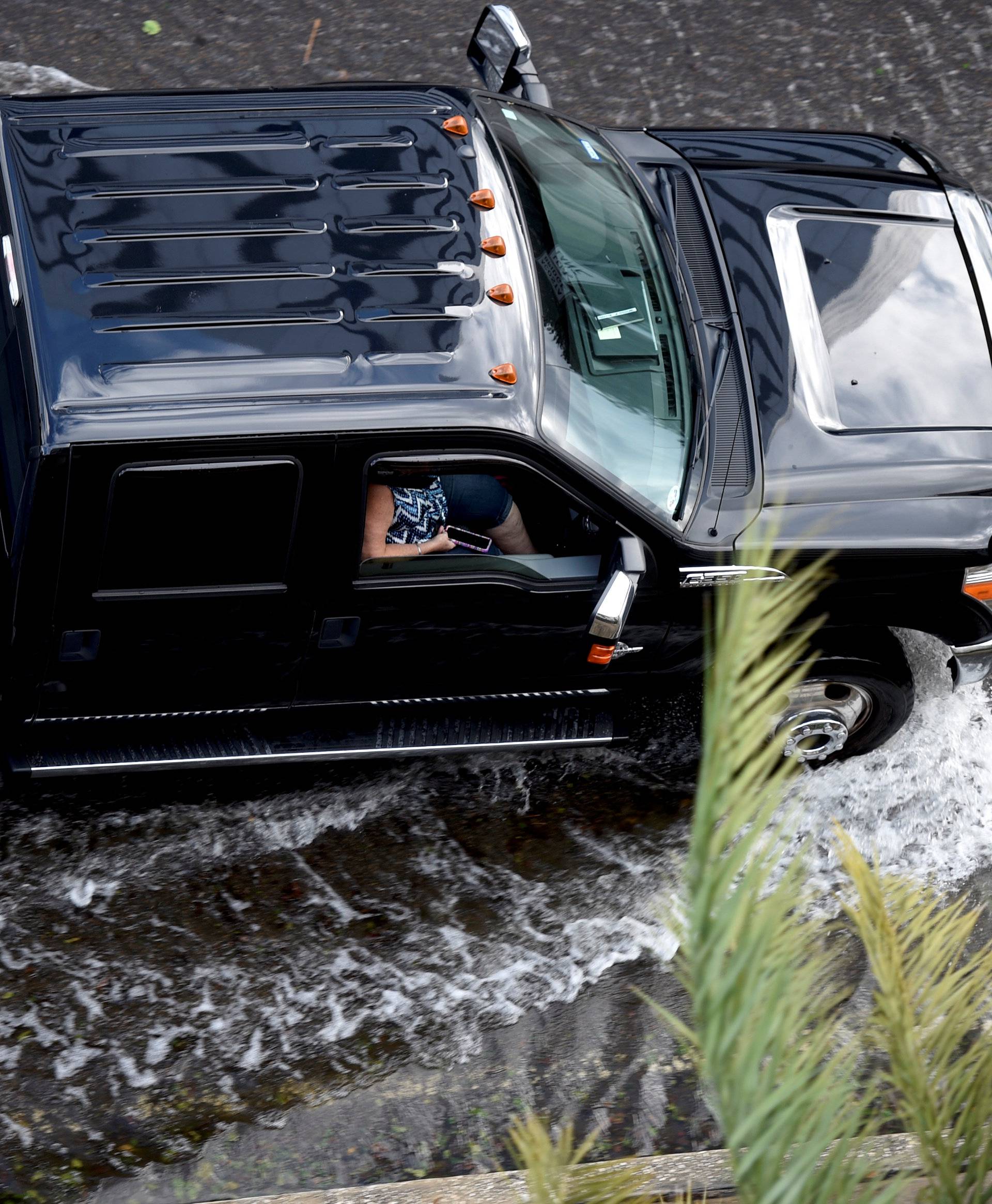 A woman uses her phone while driving through floodwaters after Hurricane Irma