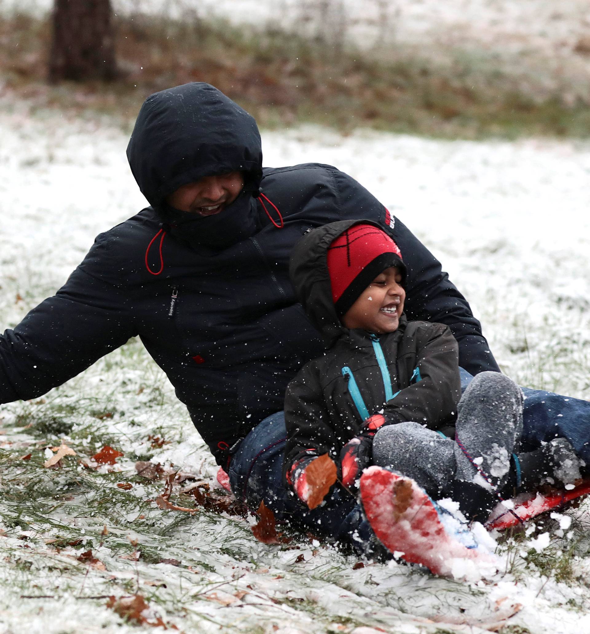 People sled down a hill in the snow in Greenwich Park, London