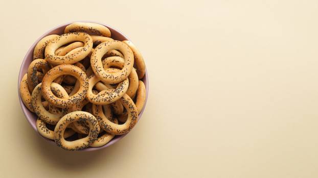 Bowl with delicious ring shaped Sushki (dry bagels) on beige bac