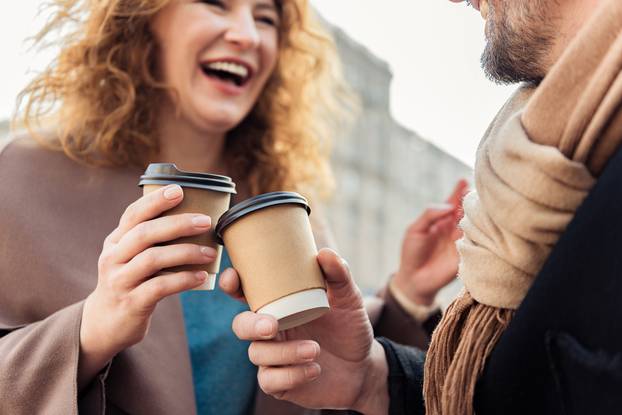 Cheerful man and woman drinking hot beverage