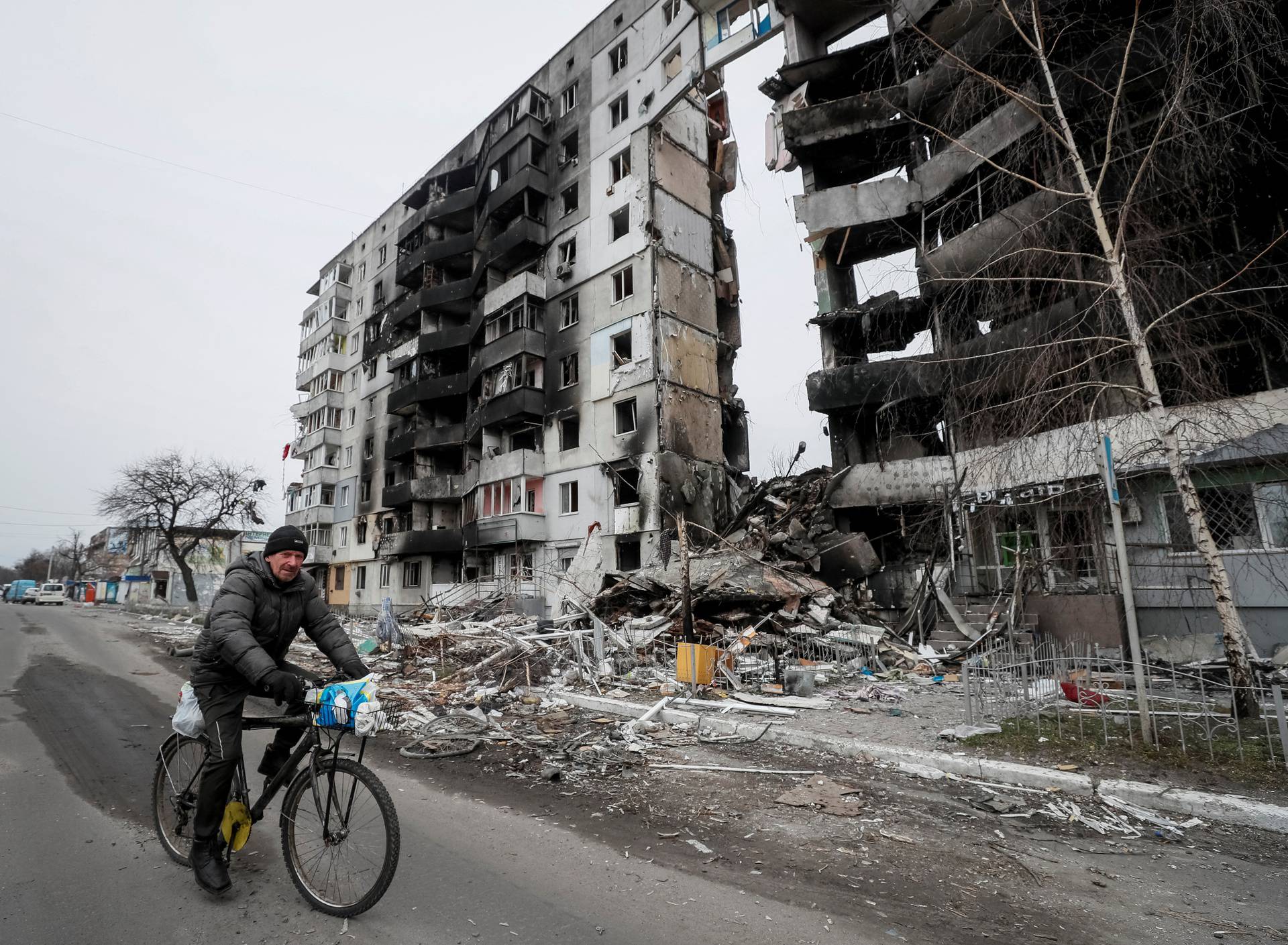 A local resident rides a bike near destroyed houses in Borodyanka