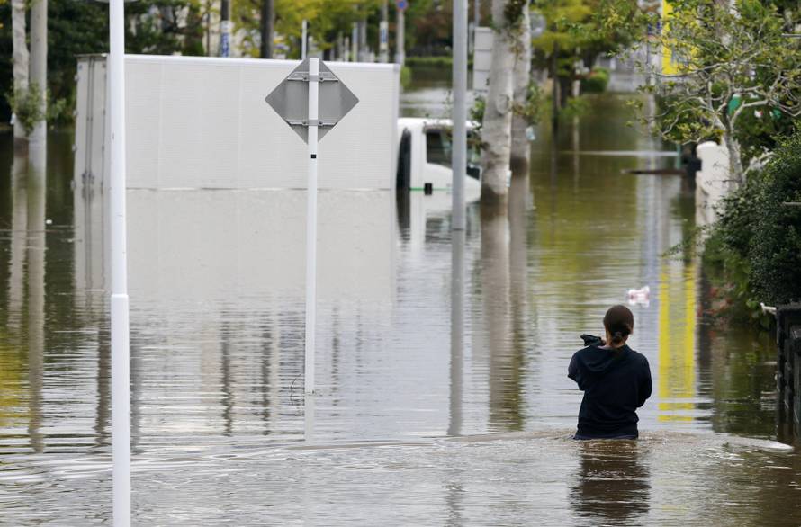 A woman walks at a residential area flooded due to heavy rain caused by Typhoon Dujuan in Sakura, Japan