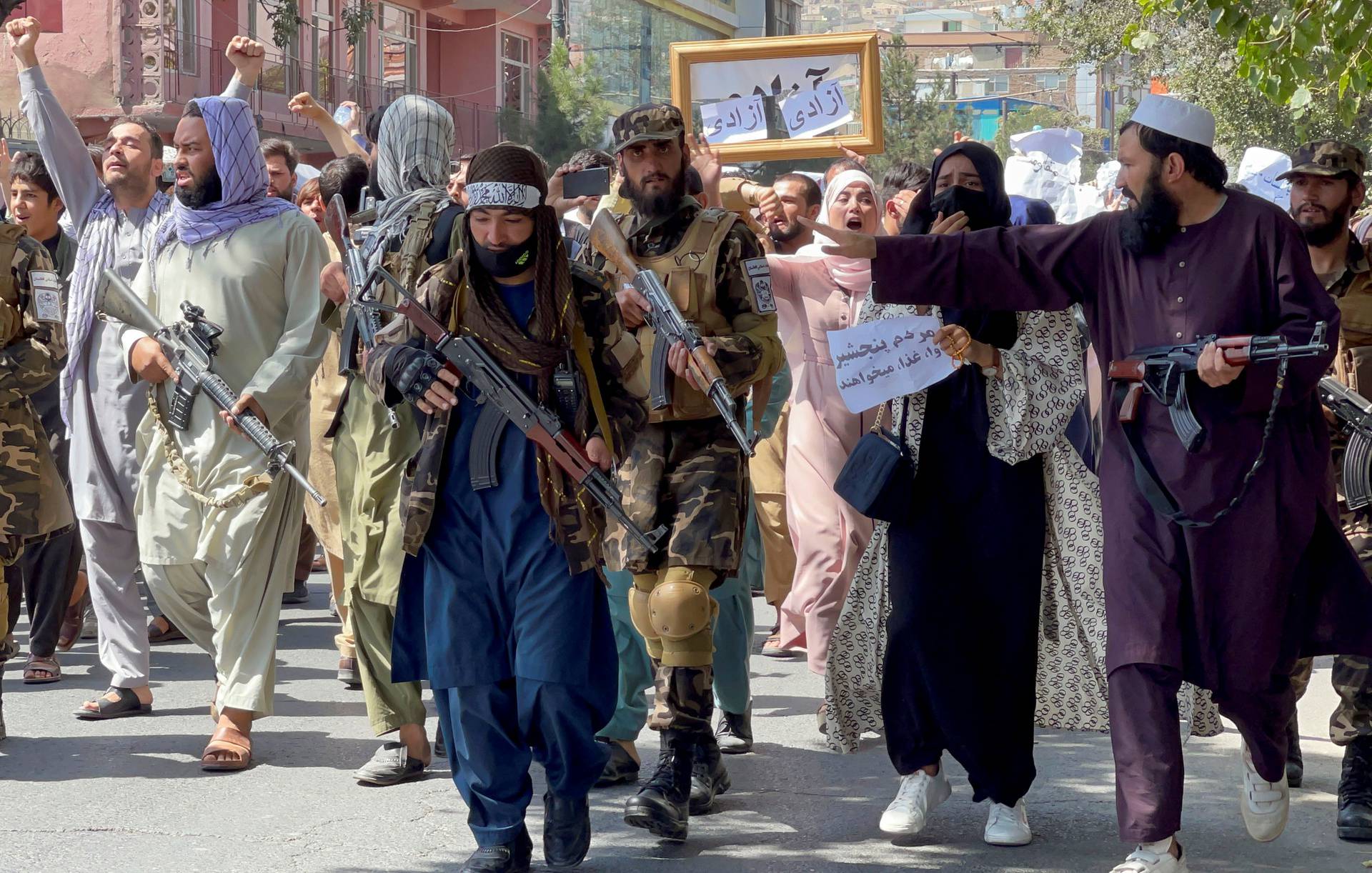 Taliban forces walk in front of Afghan demonstrators as they shout slogans during an anti-Pakistan protest, near the Pakistan embassy in Kabul, Afghanistan