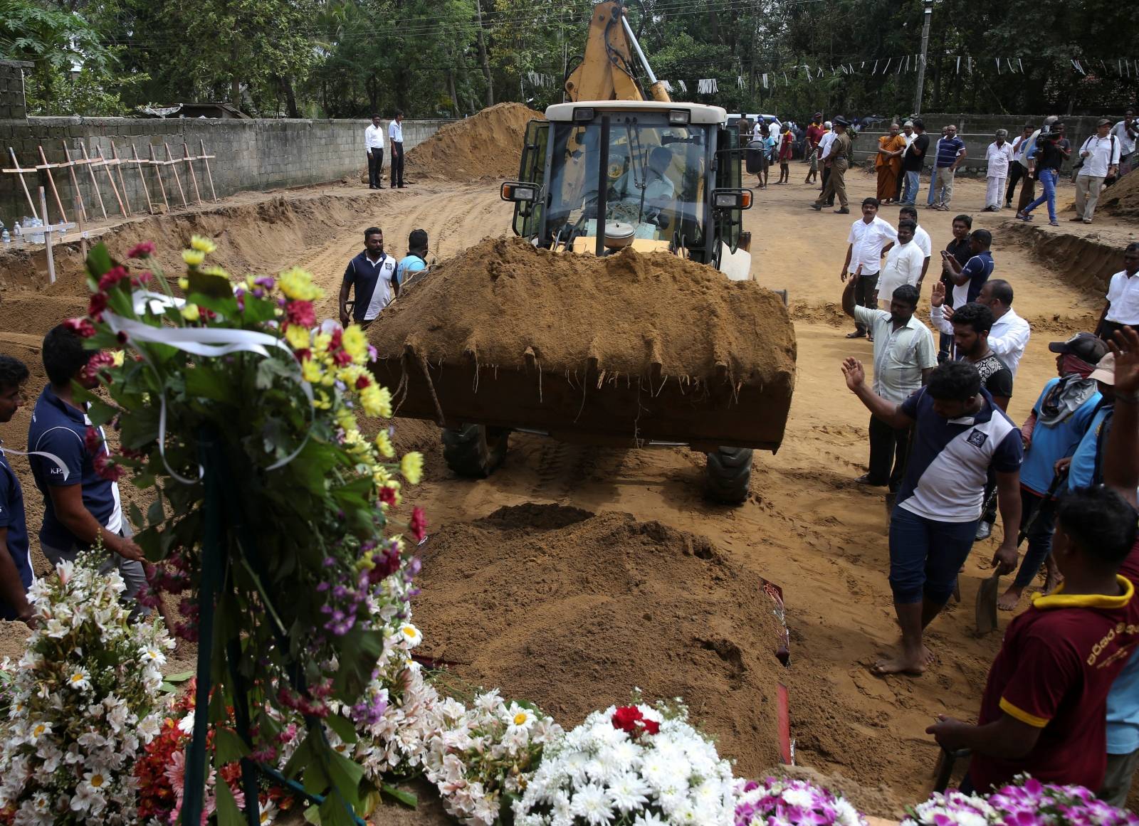 Men coordinate a mass burial of victims at a cemetery near St. Sebastian Church in Negombo