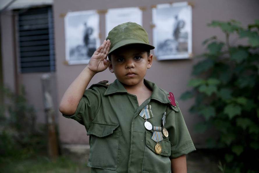 Child salutes while awaiting the caravan carrying Castro's ashes in Camaguey