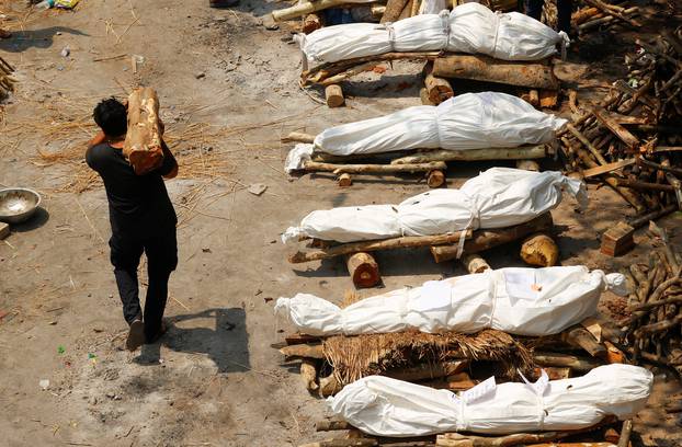 A man carrying wood walks past the funeral pyres at a crematorium in New Delhi