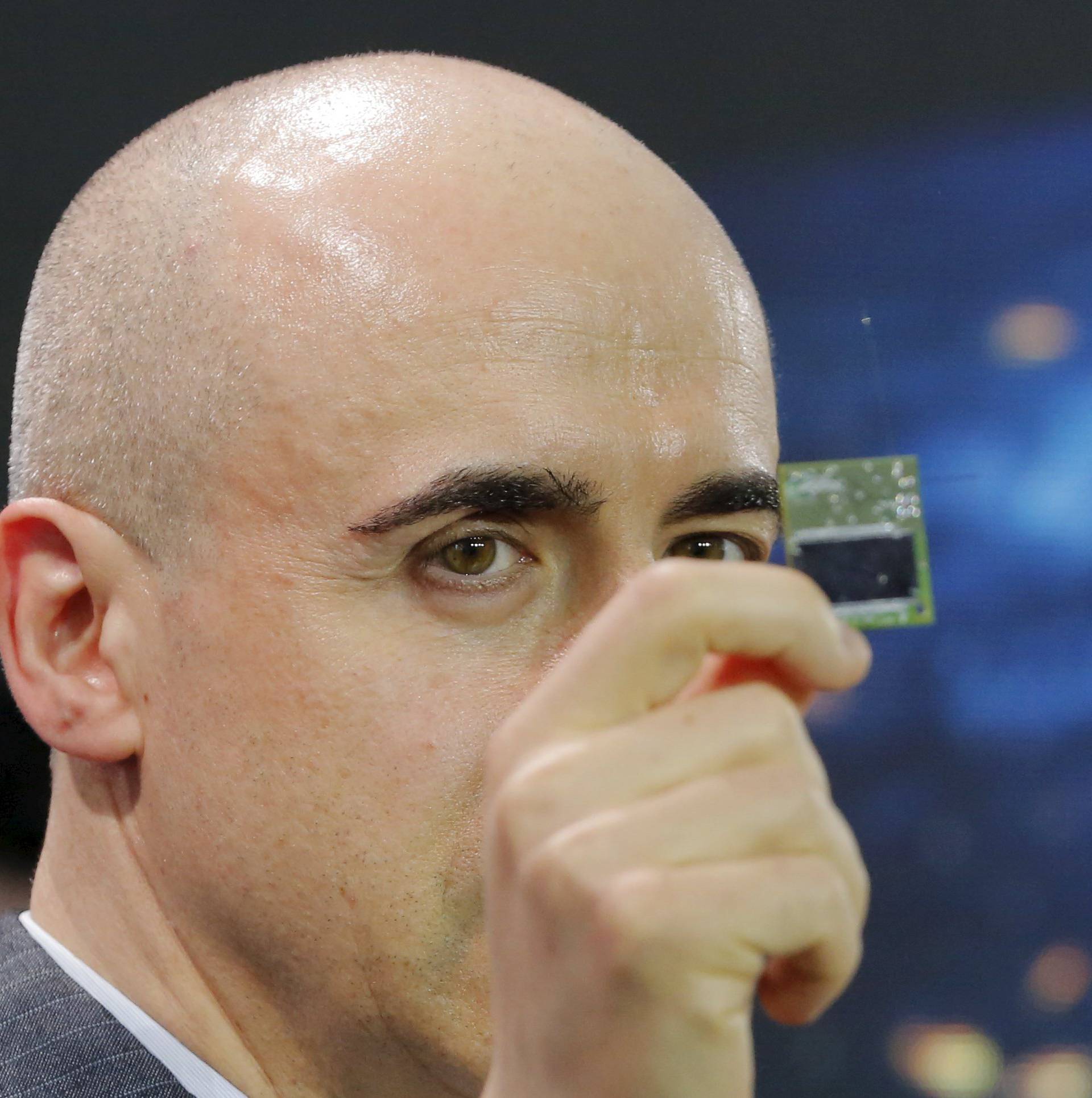 Investor Yuri Milner holds a small chip during an announcement of the Breakthrough Starshot initiative with physicist Stephen Hawking in New York