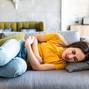 Sick woman lying on sofa in the living room with stomach ache