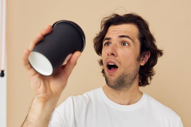 man in a white T-shirt with a black glass in hand Lifestyle unaltered