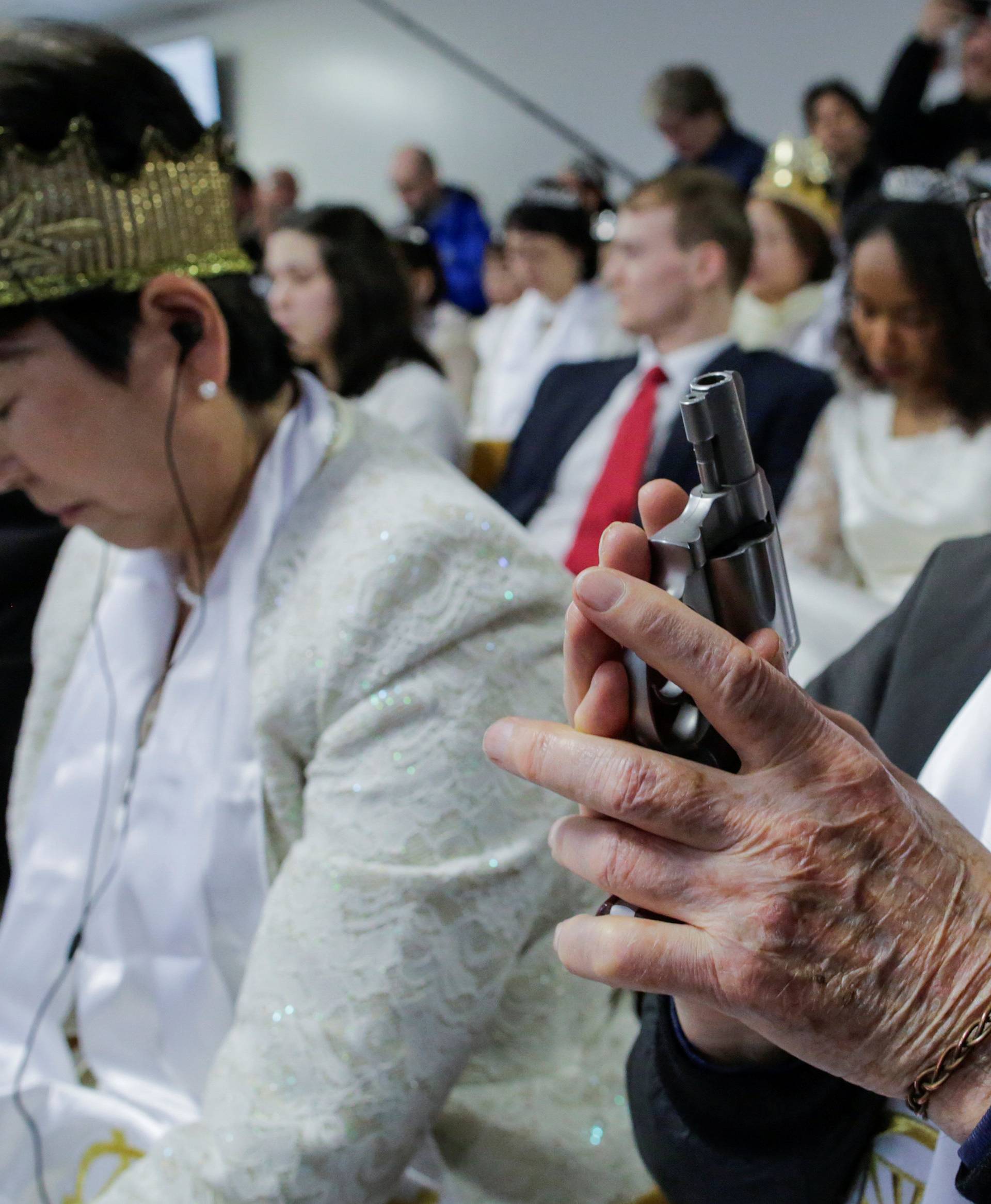 A man holds his gun as people with their AR-15-style rifles pray during a blessing ceremony at the Sanctuary Church in Newfoundland