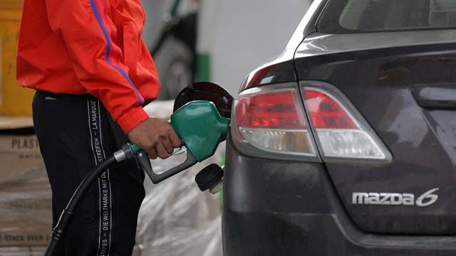 FILE PHOTO: A person uses a petrol pump at a gas station as fuel prices surged in Manhattan, New York City