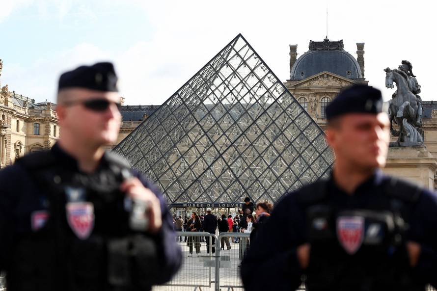 French CRS riot police stand near the glass Pyramid of the Louvre Museum