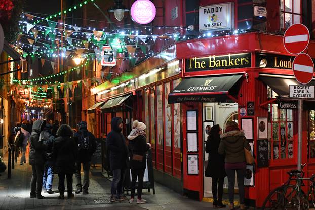People walk under Christmas lights illuminating a street in Dublin