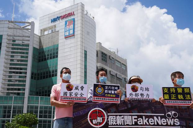 Pro-government supporters hold signs against Apple Daily outside the headquarters of Apple Daily and Next Media after police arrested five Apple Daily executives who were suspected to have breached the new national security law, in Hong Kong