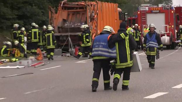 A still image taken from a video shows firefighters at a garbage truck which tipped over and landed on a car in Nagold