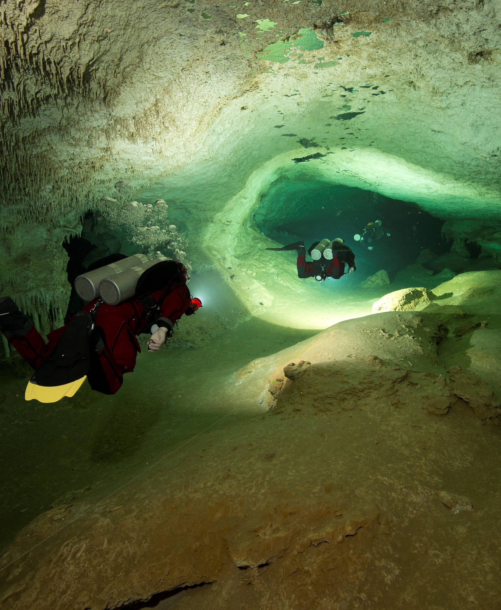 Scuba divers tour an authorized area of Sac Aktun underwater cave system as part of the Gran Acuifero Maya Project near Tulum
