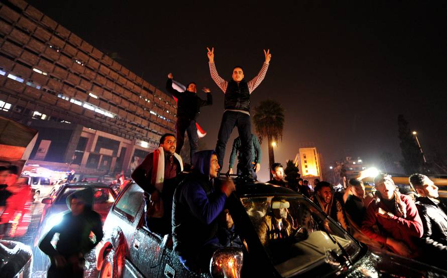 Supporters of Syria's President Bashar al-Assad carry their national flags and gesture as they tour the streets in celebration of what they say is the Syrian army's victory against the rebels in Aleppo