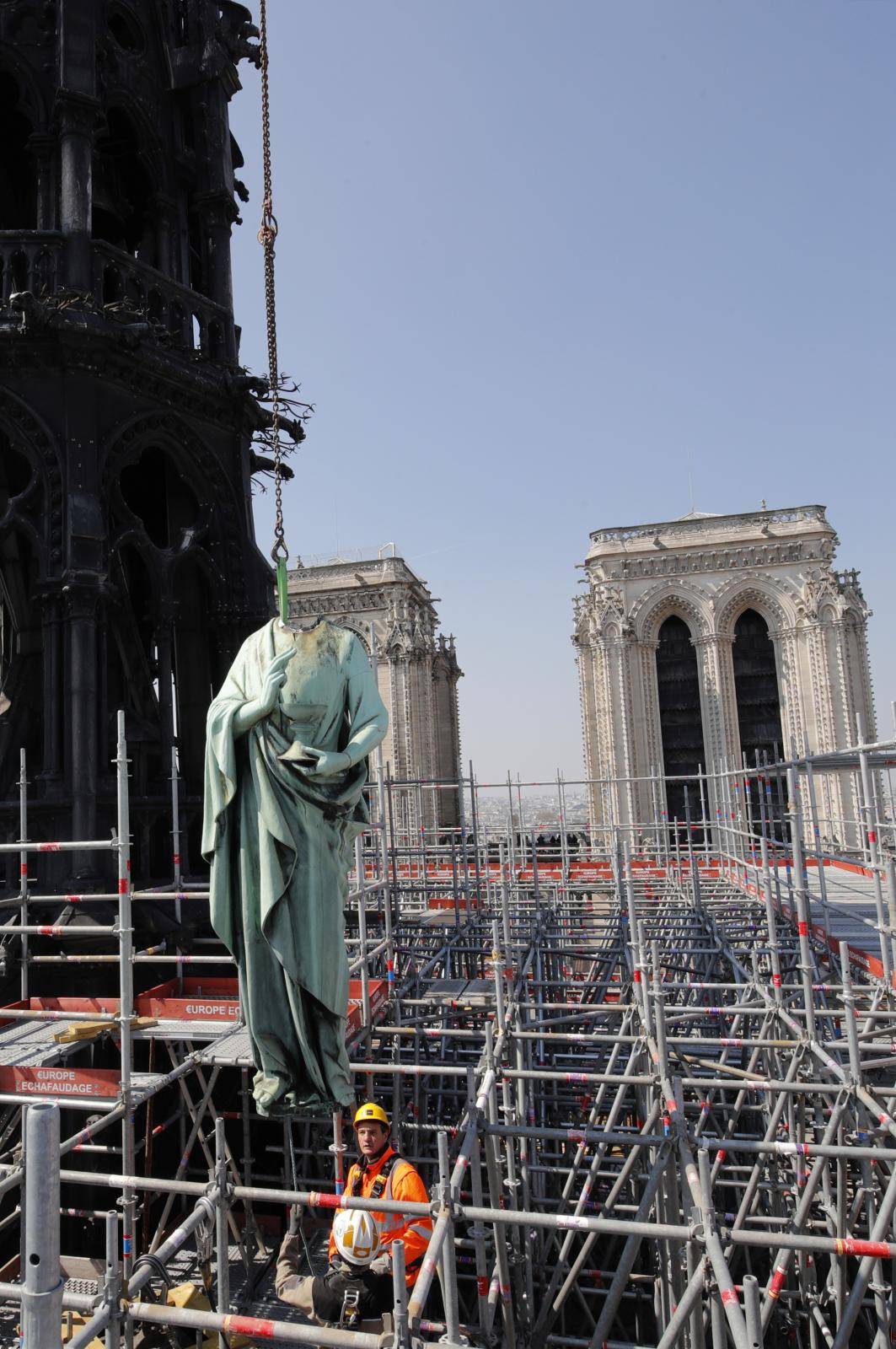 A statue of Saint John is removed from the spire of Notre Dame cathedral by a crane before restoration work, in Paris