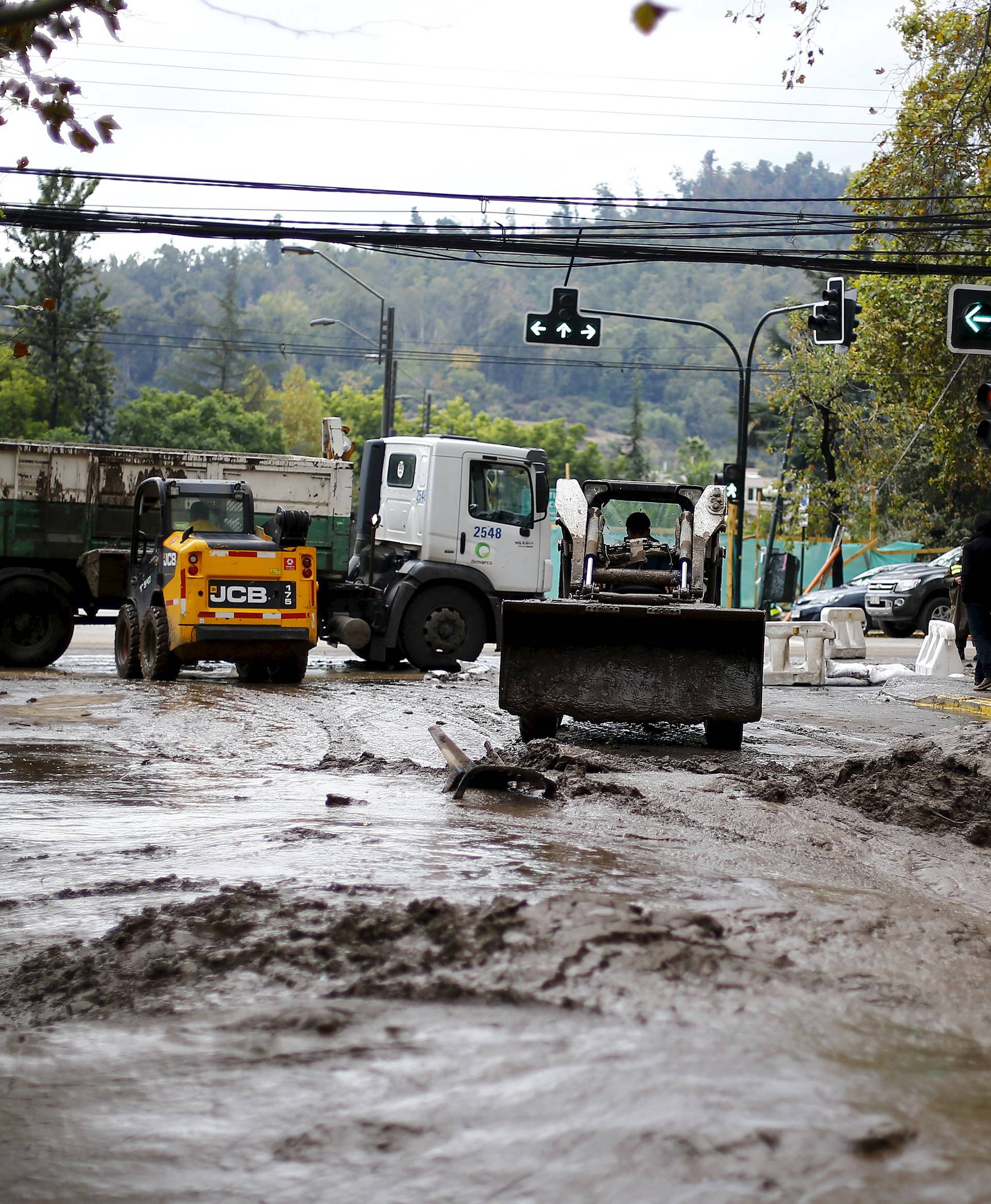 A loader removes mud in a street after a flood in Santiago