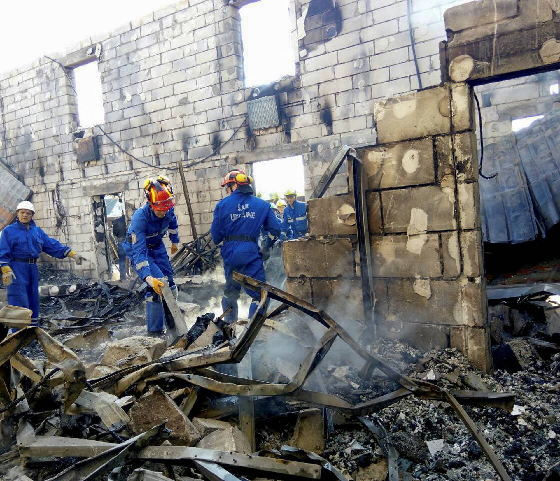 Rescuers inspect the debris of a residential house after a fire broke out, in the village of Litochky