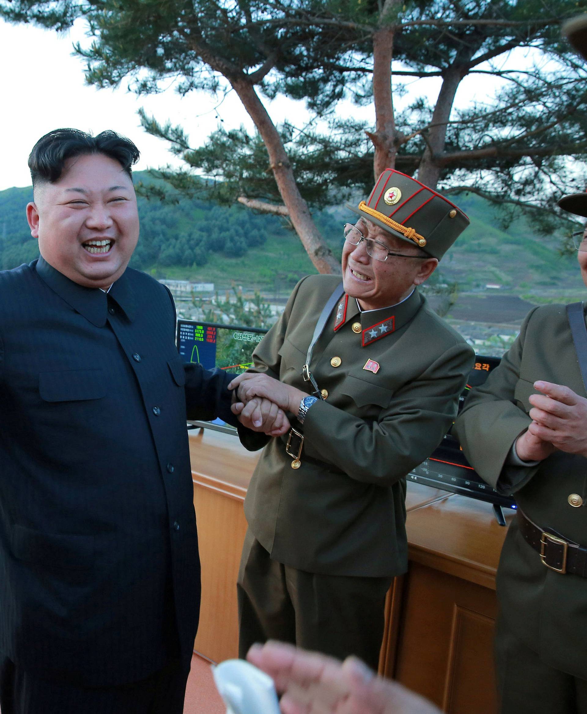 North Korean leader Kim Jong Un reacts with members of the Korean People's Army scientists and engineers