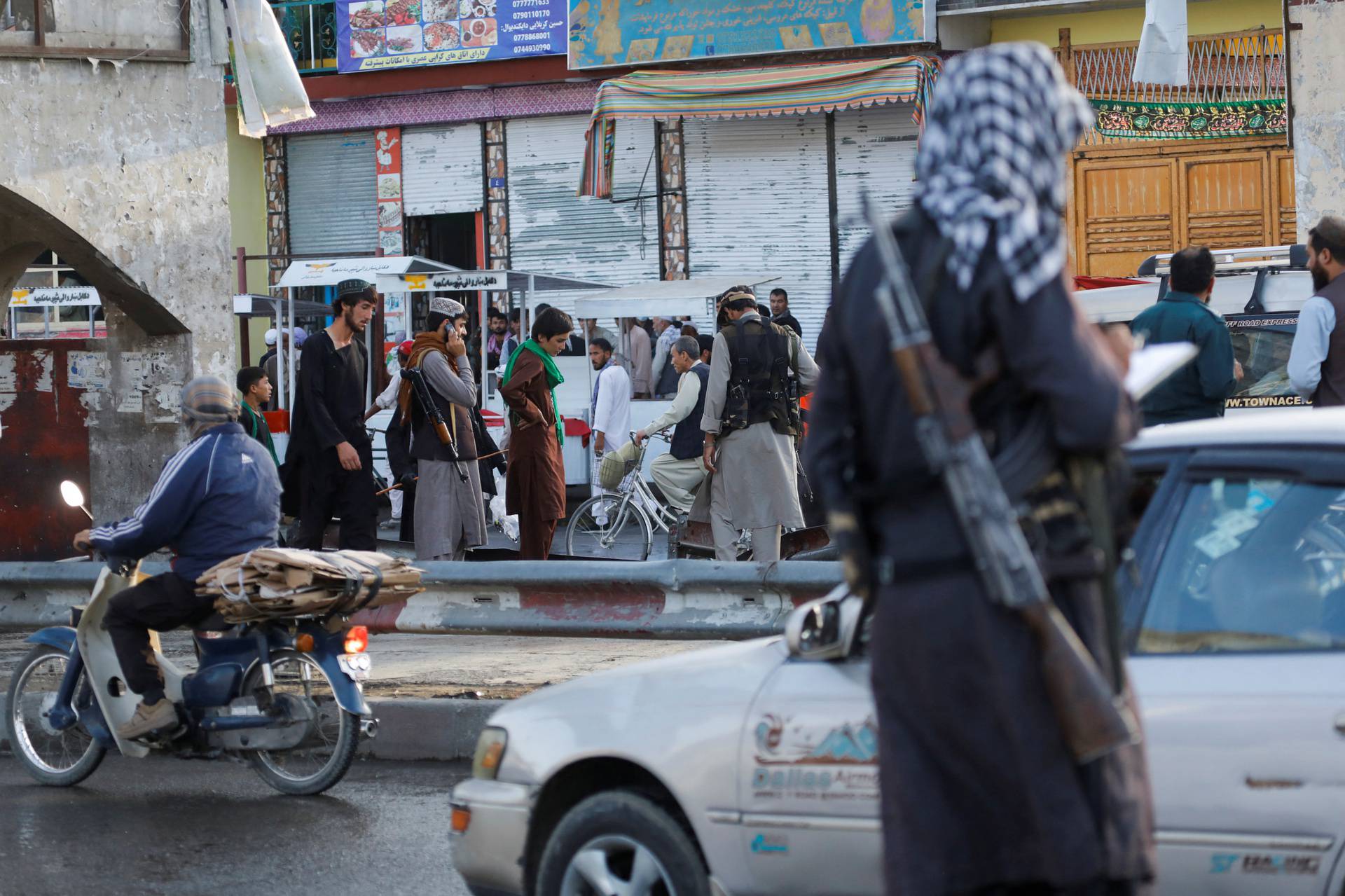 Taliban fighters stand guard at the site of a blast in Kabul