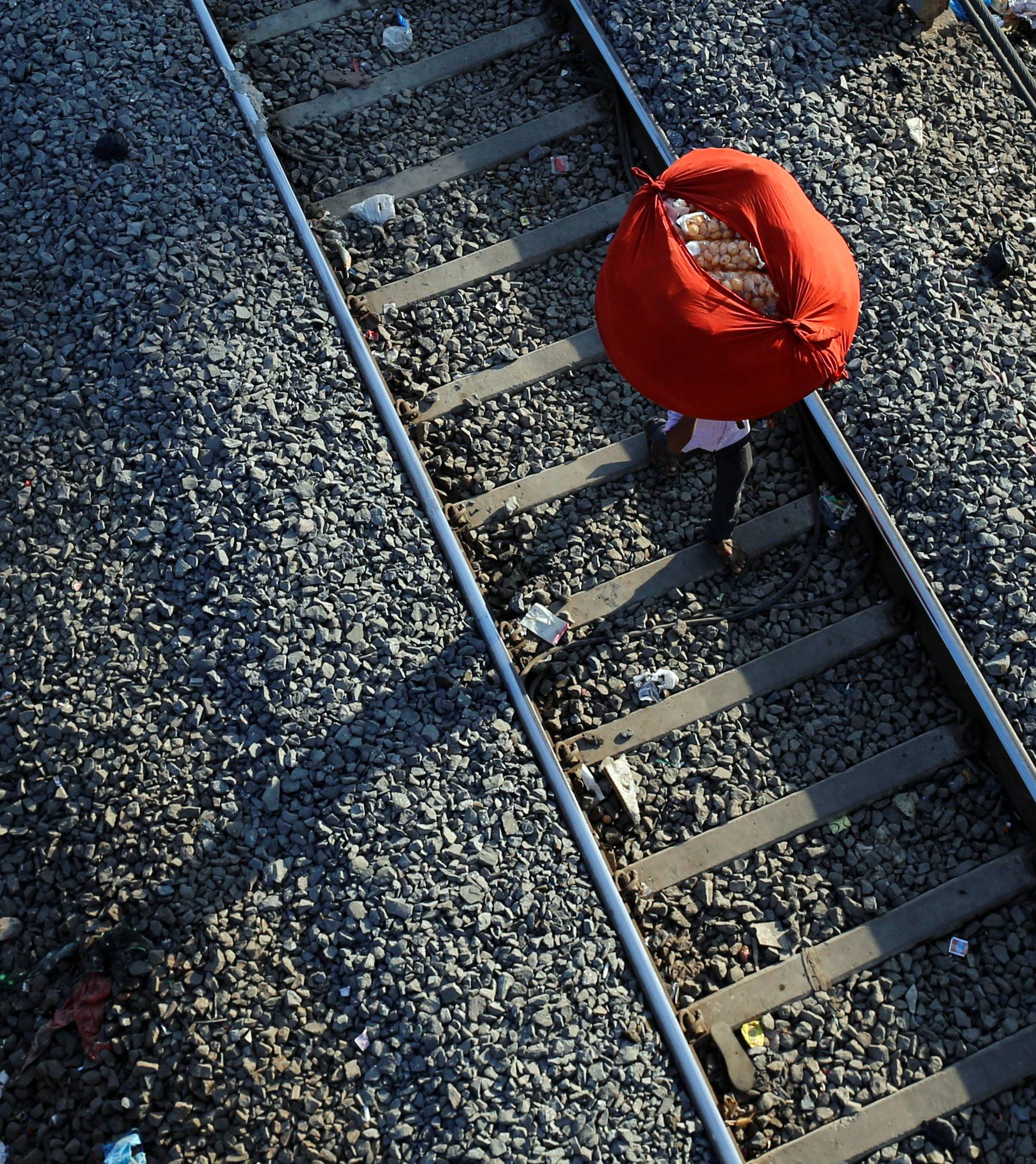 A man carries "paani puri", a traditional Indian snack, on his head on a railway track in Mumbai