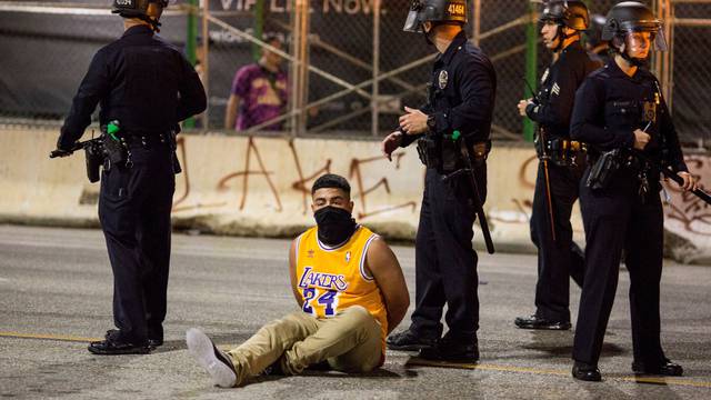 A man is detained by police outside the Staples Center as Los Angeles Lakers fans celebrate their team winning the 2020 NBA Championship against Miami Heat